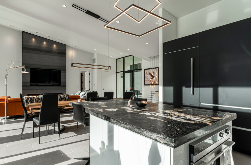 Photo of a large modern u-shaped eat-in kitchen in Seattle with flat-panel cabinets, black cabinets, granite benchtops, white splashback, stainless steel appliances, porcelain floors, with island, grey floor and multi-coloured benchtop.