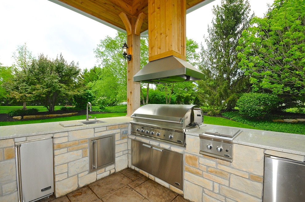 Design ideas for a large traditional backyard patio in Indianapolis with an outdoor kitchen, stamped concrete and a roof extension.