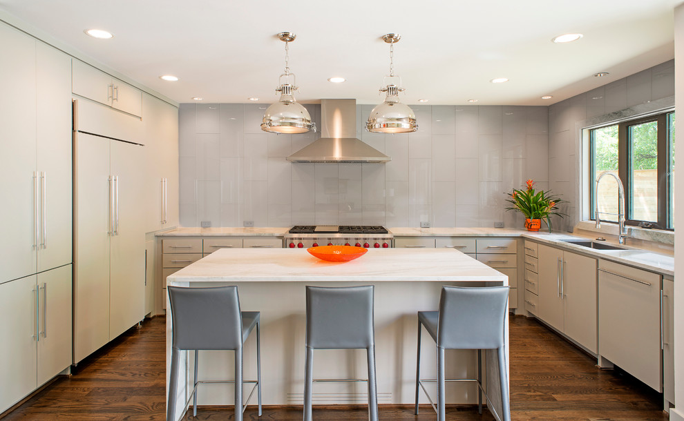 This is an example of a mid-sized transitional u-shaped kitchen in Dallas with an undermount sink, flat-panel cabinets, beige cabinets, recycled glass benchtops, grey splashback, glass tile splashback, panelled appliances, dark hardwood floors and with island.