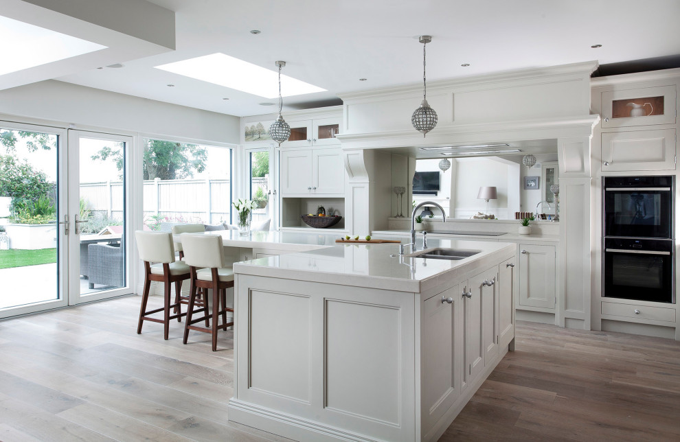 Design ideas for a large contemporary l-shaped eat-in kitchen in Other with shaker cabinets, white cabinets, quartz benchtops, black appliances, with island and white benchtop.