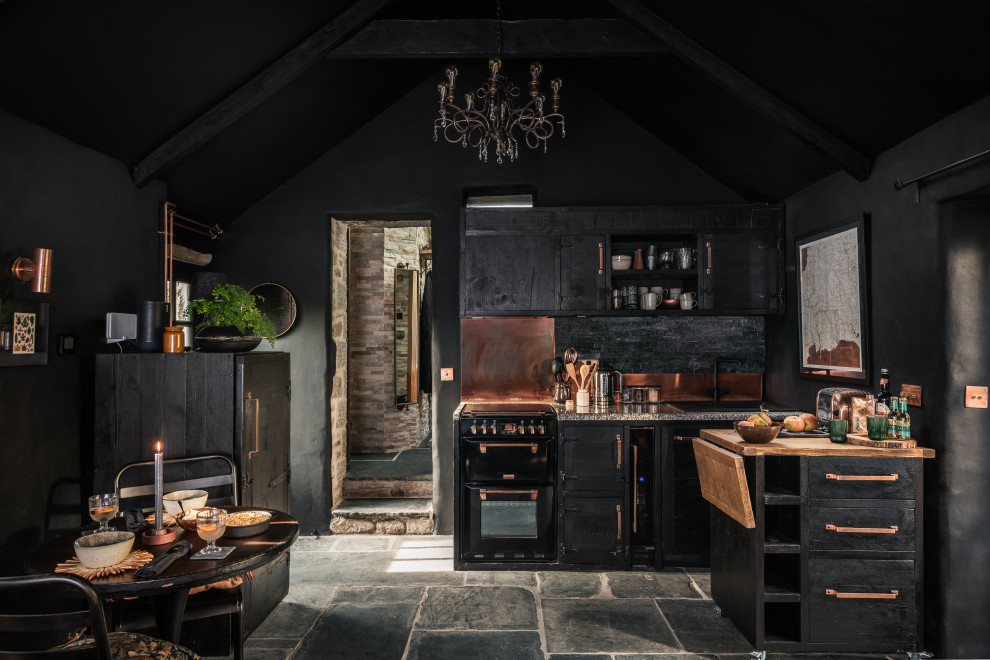 This is an example of a small farmhouse l-shaped kitchen in Cornwall with black cabinets, metallic splashback, black appliances and grey floors.