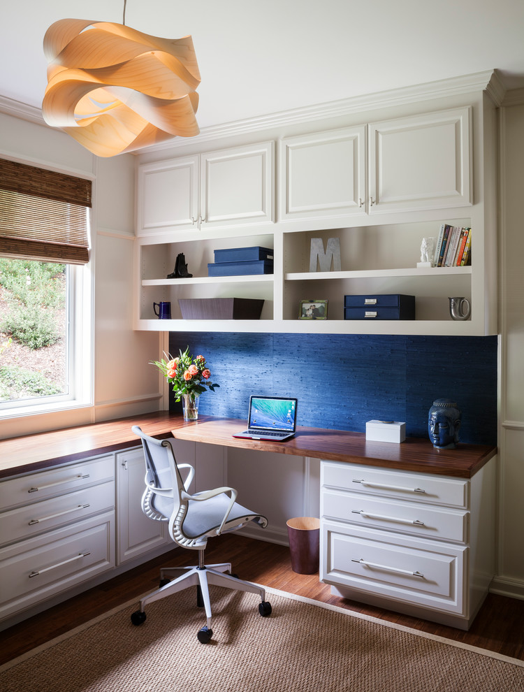 Imagen de despacho bohemio de tamaño medio con paredes azules, suelo de bambú y escritorio empotrado