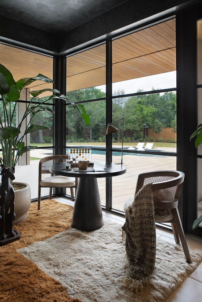 Hill Country Modern Meets Southlake, Texas - This Hill Country Modern home in Southlake combines modern design with comfort, featuring light-filled spaces and unique details reflecting the family's eclectic style for play and sophistication. 

This lounge features a floor-to-ceiling corner window with panoramic views. The dark palette is complemented by cozy furniture and statement lighting, creating an inviting and sophisticated atmosphere.