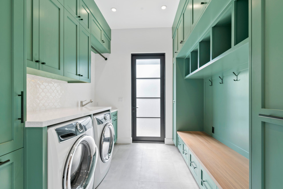 Photo of a mid-sized country single-wall utility room in San Francisco with shaker cabinets, green cabinets, grey walls, concrete floors, a side-by-side washer and dryer and grey floor.