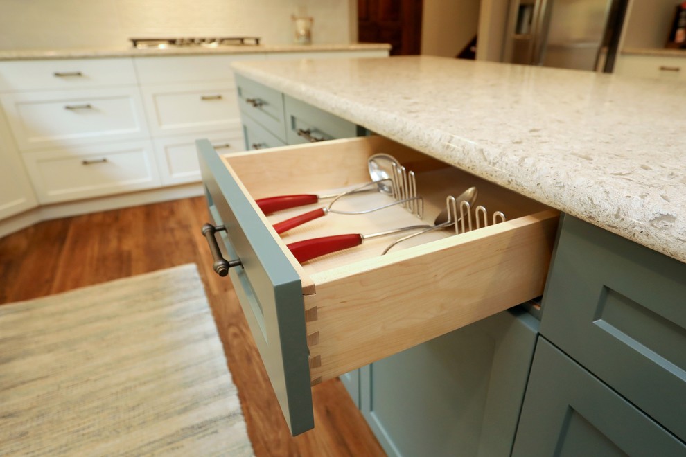 Inspiration for a transitional vinyl floor and brown floor kitchen remodel with an undermount sink, white cabinets, quartz countertops, white backsplash, subway tile backsplash, stainless steel appliances, an island and beige countertops