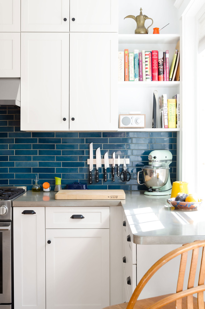 Design ideas for a mid-sized eclectic u-shaped separate kitchen in Boston with an undermount sink, recessed-panel cabinets, white cabinets, concrete benchtops, blue splashback, subway tile splashback, white appliances, light hardwood floors, no island and brown floor.