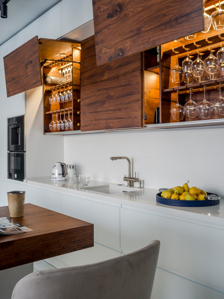 Offene, Einzeilige Moderne Küche mit Glasfronten, weißen Schränken, Küchenrückwand in Weiß, Kücheninsel und weißer Arbeitsplatte in Sonstige