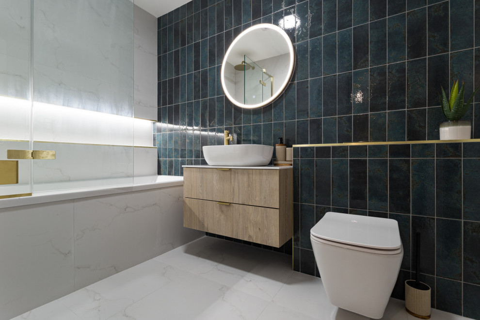 Inspiration for a mid-sized modern kids bathroom in Dublin with flat-panel cabinets, medium wood cabinets, a drop-in tub, a wall-mount toilet, green tile, subway tile, white walls, marble floors, a vessel sink, limestone benchtops, white floor, white benchtops, a niche, a single vanity and a floating vanity.