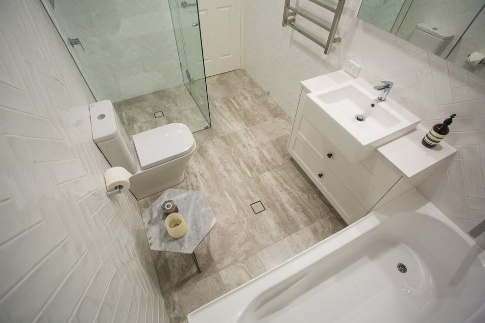 Large modern master bathroom in Brisbane with shaker cabinets, a double shower, a one-piece toilet, white tile, subway tile, white walls, porcelain floors, an undermount sink, solid surface benchtops, multi-coloured floor, a hinged shower door and white benchtops.