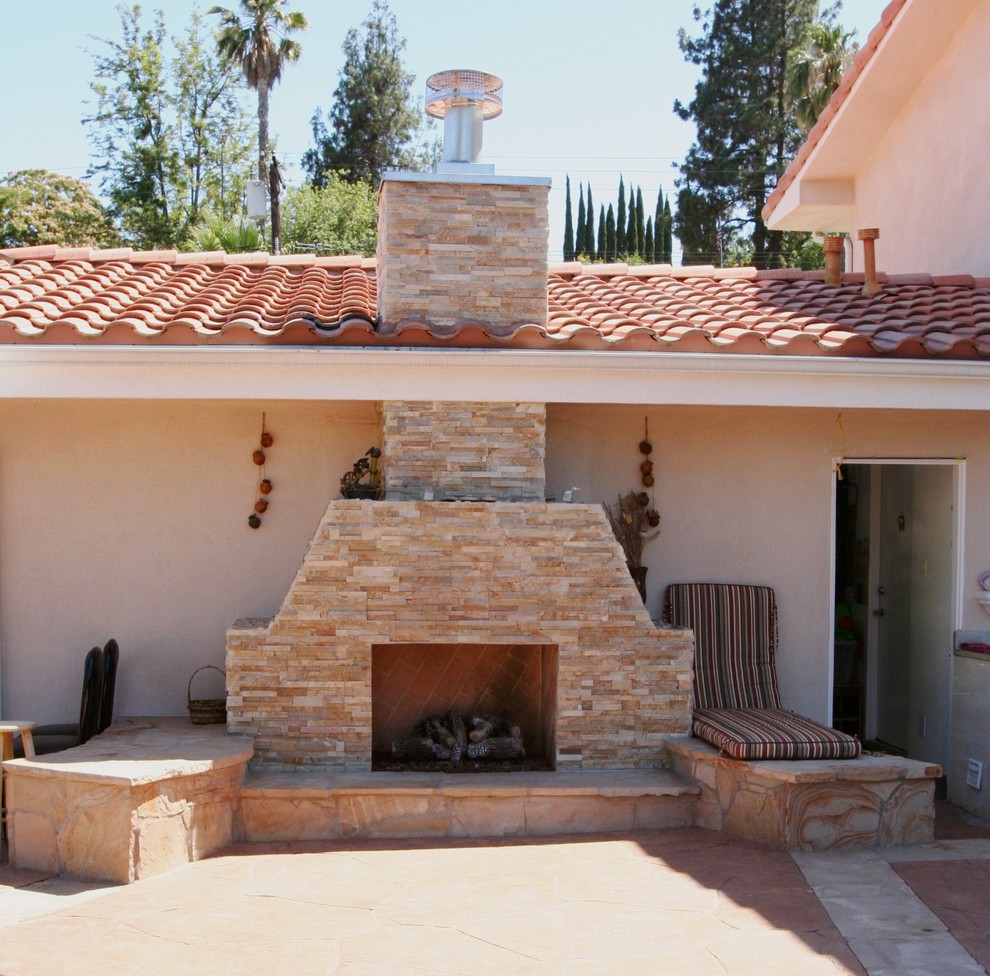 Mid-sized backyard patio in Los Angeles with a fire feature, natural stone pavers and no cover.