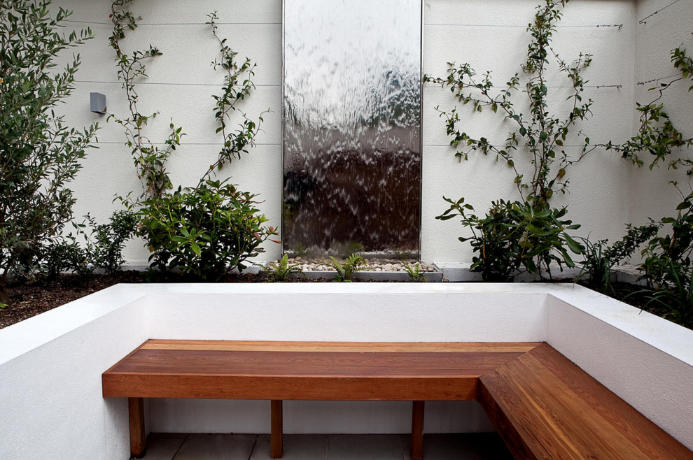 Inspiration for a contemporary courtyard garden in London with a water feature and concrete pavers.