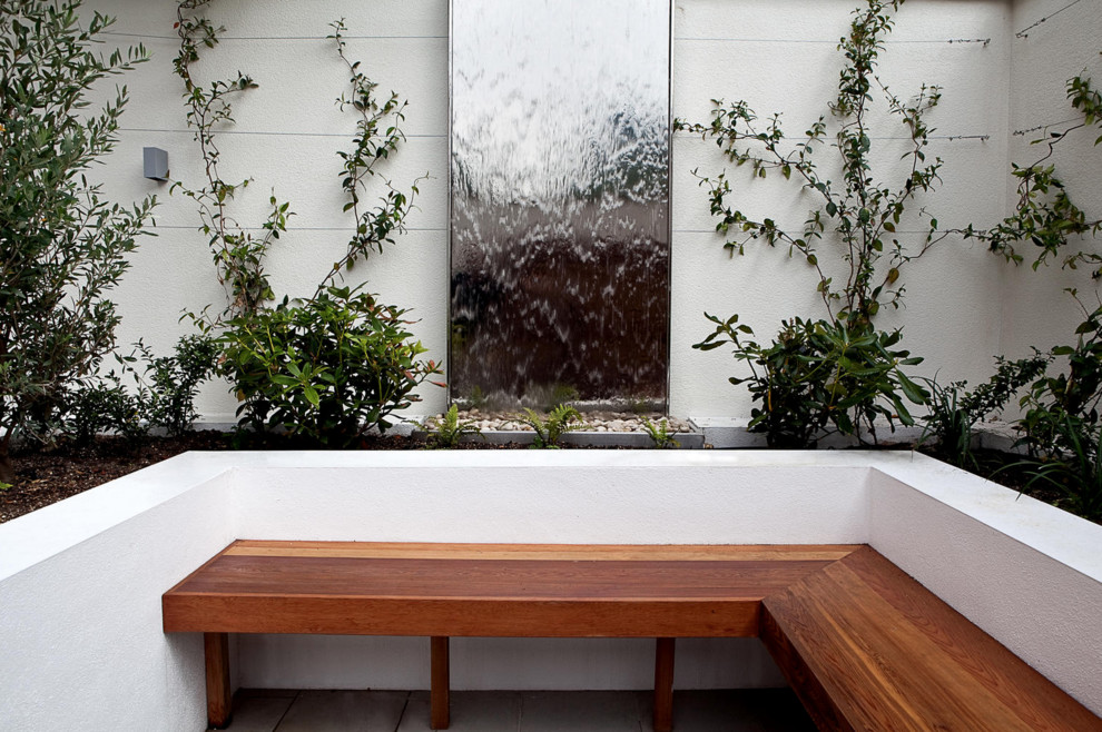 Inspiration for a contemporary courtyard concrete paver water fountain landscape in London.