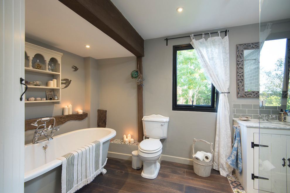 Design ideas for a country master bathroom in Buckinghamshire with white cabinets, a claw-foot tub, a two-piece toilet, gray tile, subway tile, grey walls, dark hardwood floors, an undermount sink, brown floor and grey benchtops.