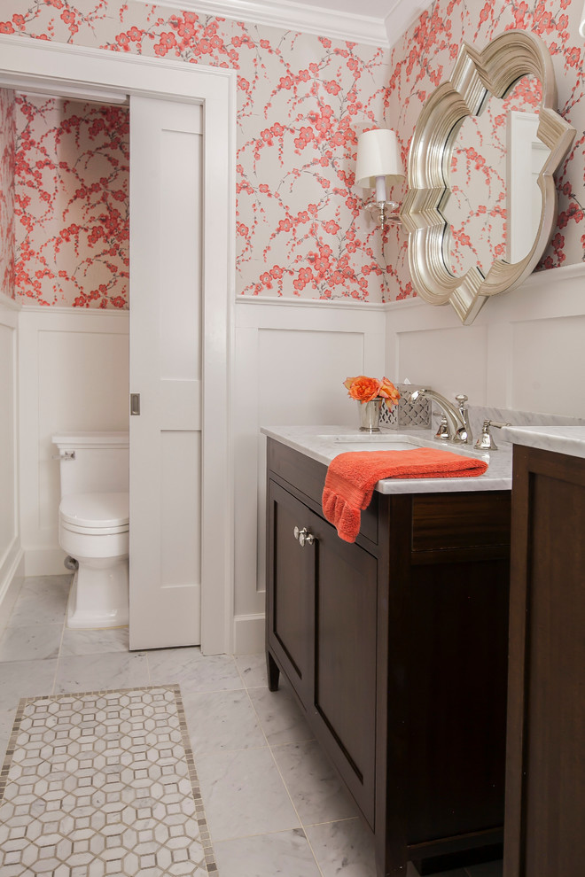This is an example of a transitional bathroom in New York with shaker cabinets, dark wood cabinets, a two-piece toilet, multi-coloured walls, an undermount sink, grey floor and white benchtops.
