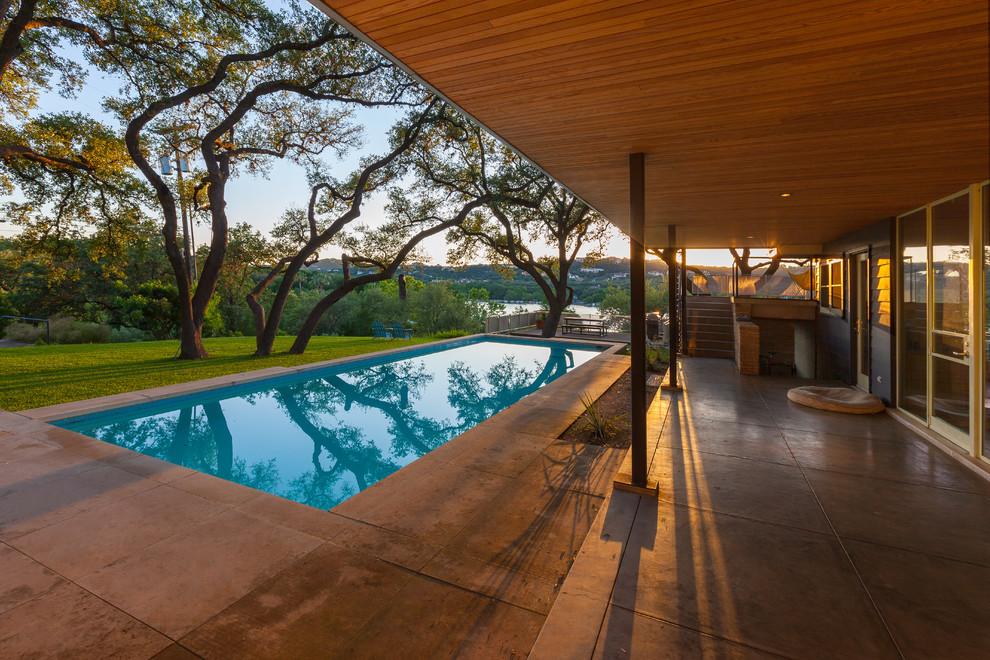Design ideas for a mid-sized midcentury backyard rectangular lap pool in Austin with concrete slab.