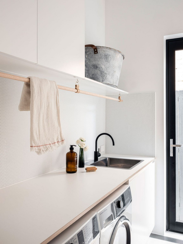 This is an example of a small modern single-wall utility room in Perth with a drop-in sink, recessed-panel cabinets, light wood cabinets, quartz benchtops, ceramic splashback, a side-by-side washer and dryer and white benchtop.