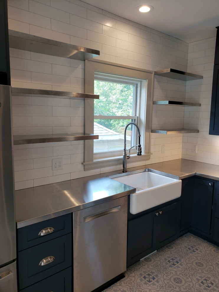 Enclosed kitchen - large modern u-shaped porcelain tile and multicolored floor enclosed kitchen idea in Grand Rapids with a farmhouse sink, shaker cabinets, blue cabinets, wood countertops, white backsplash, subway tile backsplash, stainless steel appliances and a peninsula
