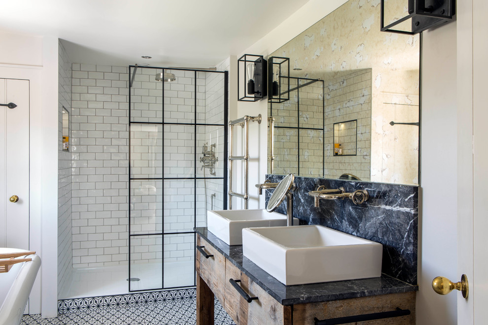 This is an example of a mid-sized contemporary bathroom in Oxfordshire with flat-panel cabinets, light wood cabinets, an open shower, white walls, a vessel sink, marble benchtops, multi-coloured floor, an open shower and black benchtops.
