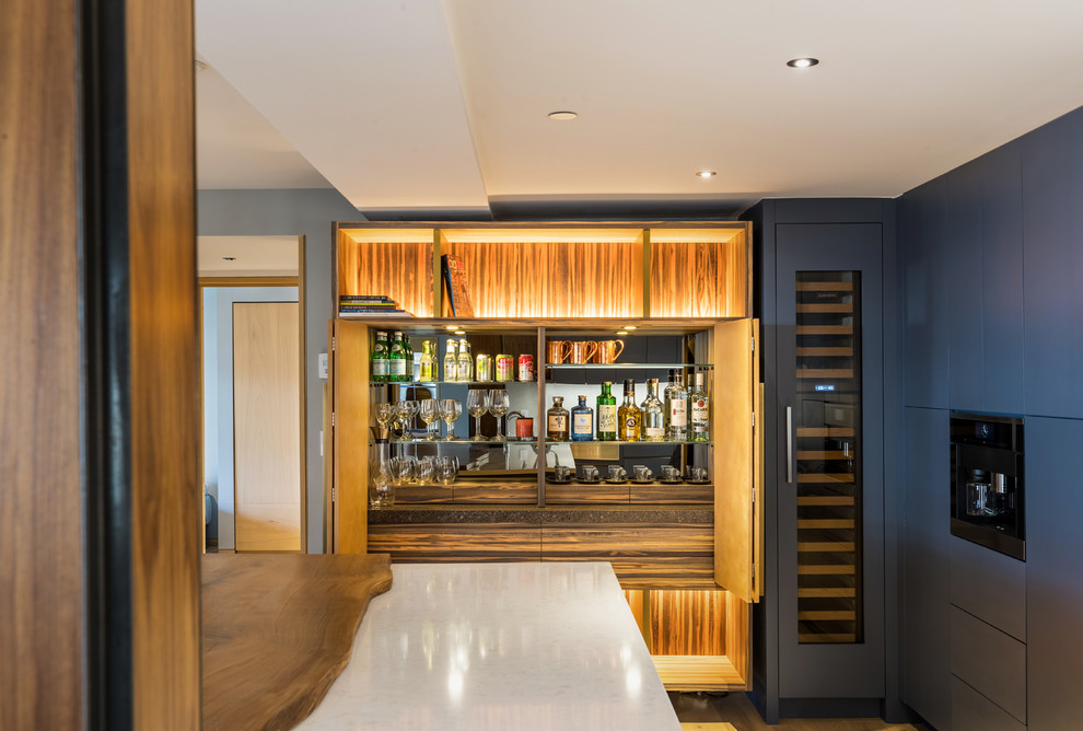 Mid-sized modern single-wall home bar in Denver with flat-panel cabinets, grey cabinets, light hardwood floors, brown floor, quartzite benchtops, mirror splashback and white benchtop.