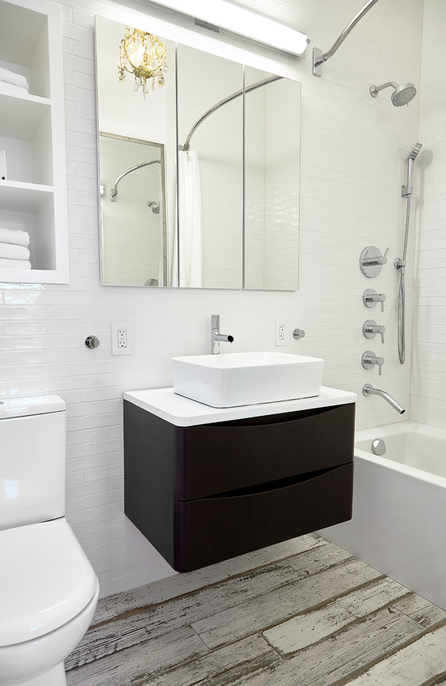 Design ideas for a small contemporary master bathroom in New York with an alcove tub, a shower/bathtub combo, a one-piece toilet, white tile, subway tile, white walls, solid surface benchtops, flat-panel cabinets, dark wood cabinets, porcelain floors and a vessel sink.
