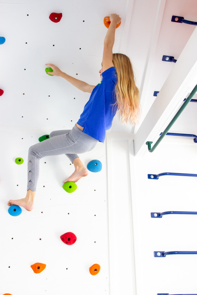Photo of a small modern home climbing wall in New York with white walls and grey floor.