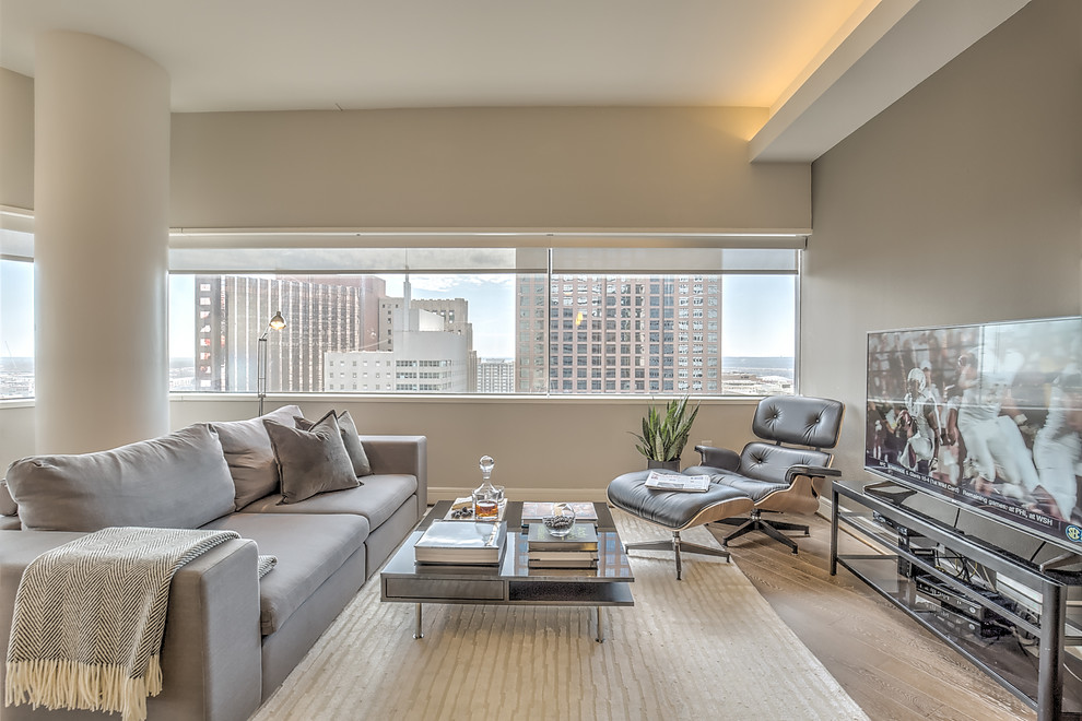 This is an example of a mid-sized modern open concept living room in Dallas with grey walls, light hardwood floors, no fireplace and a freestanding tv.