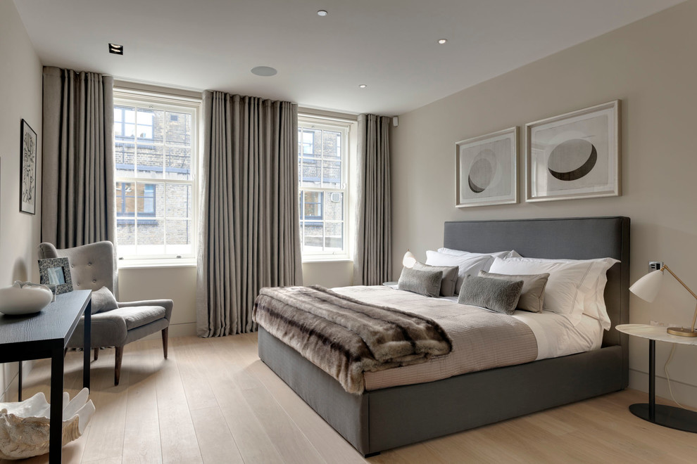 Design ideas for a transitional bedroom in London with beige walls and light hardwood floors.