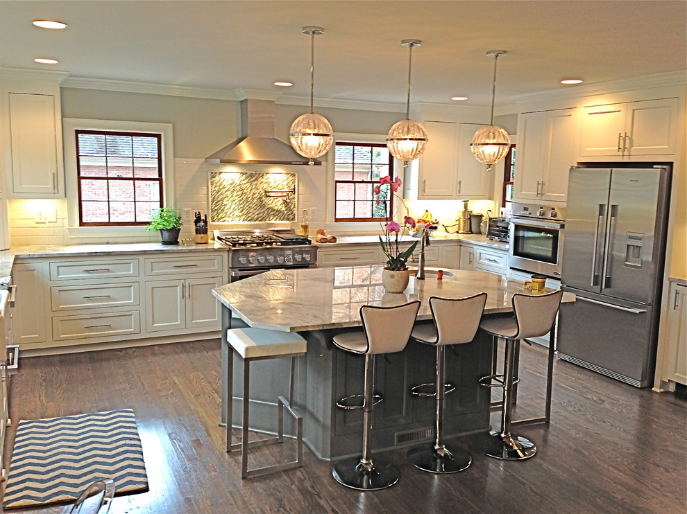 Example of a transitional u-shaped dark wood floor and brown floor eat-in kitchen design with recessed-panel cabinets, white cabinets, marble countertops, white backsplash, an island, subway tile backsplash, stainless steel appliances and a farmhouse sink