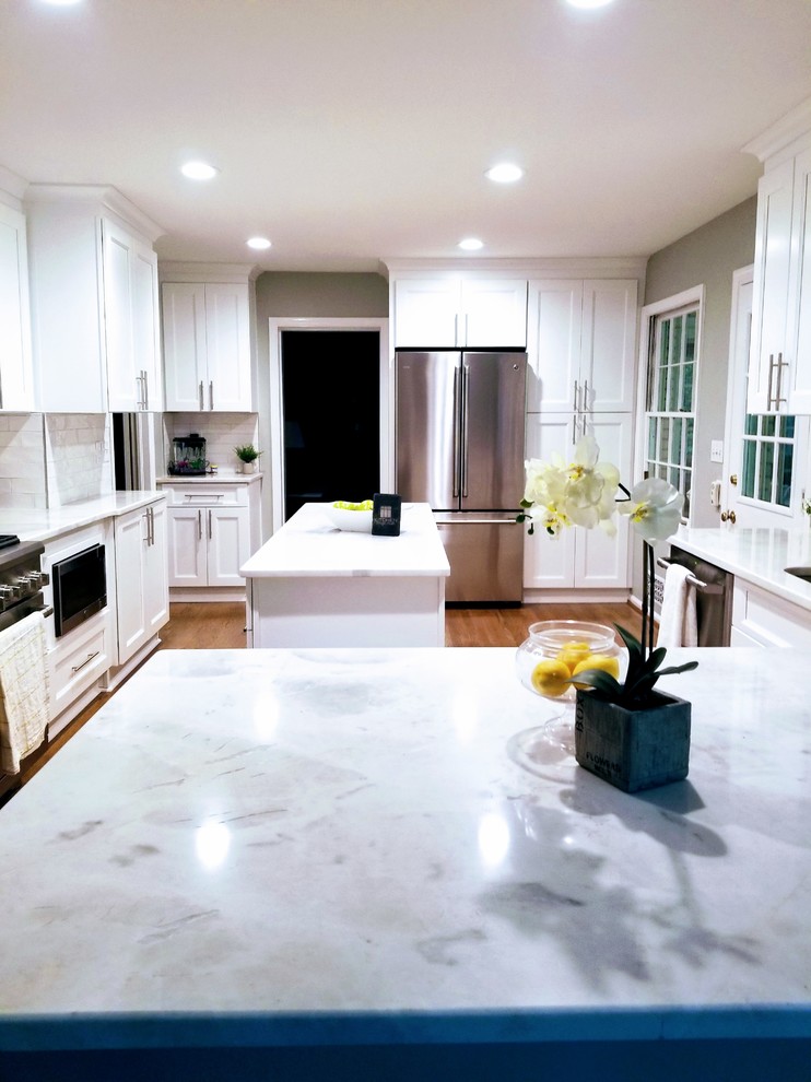 Inspiration for a large transitional u-shaped medium tone wood floor and brown floor enclosed kitchen remodel in Miami with an undermount sink, shaker cabinets, white cabinets, quartz countertops, white backsplash, subway tile backsplash, stainless steel appliances, an island and white countertops