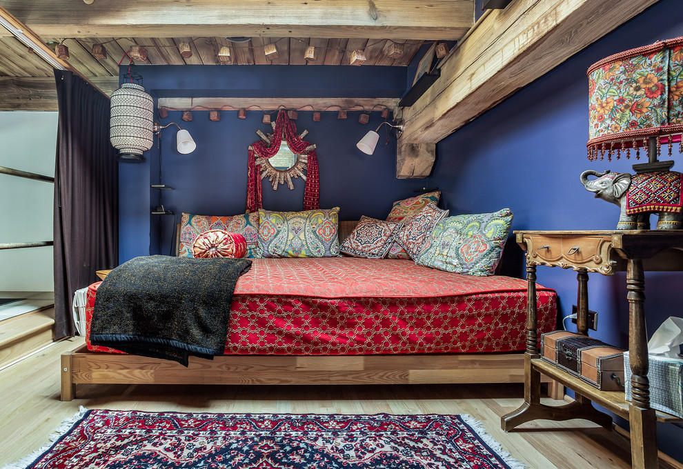 This is an example of a mid-sized country loft-style bedroom in Chicago with blue walls, light hardwood floors, brown floor and no fireplace.
