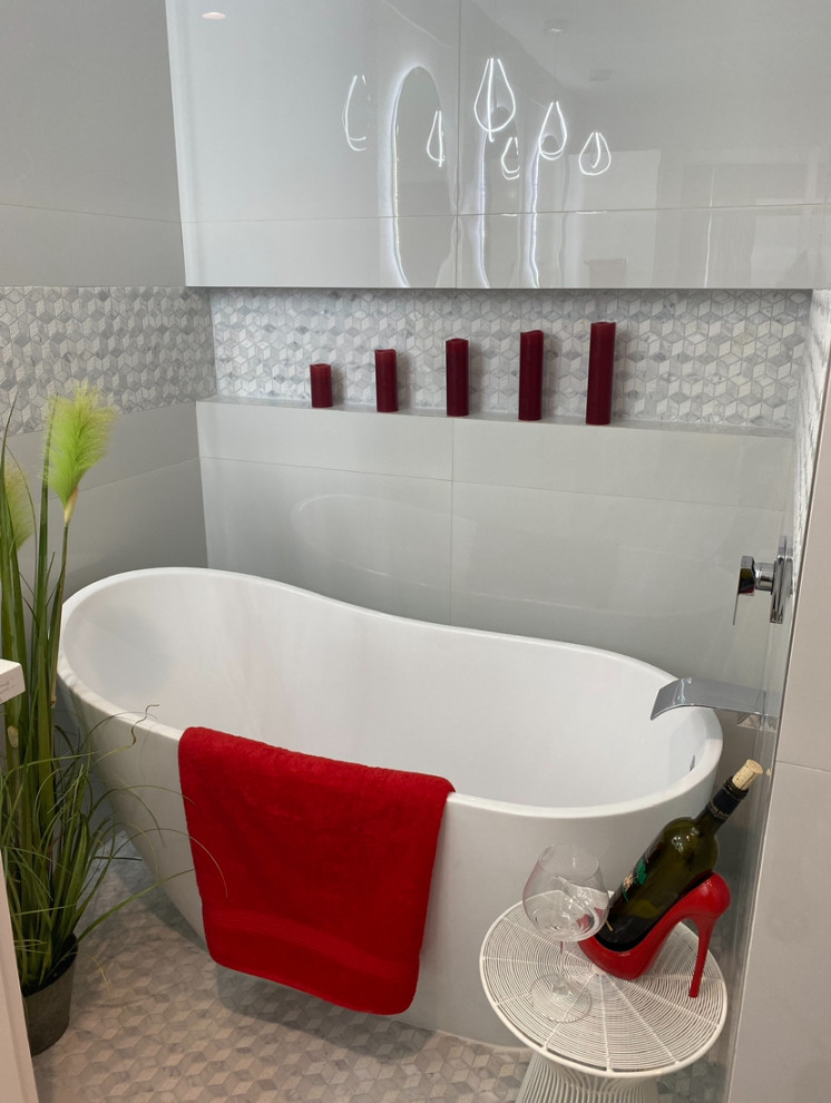 Photo of a medium sized bohemian ensuite bathroom in Houston with white cabinets, a freestanding bath, a shower/bath combination, a one-piece toilet, grey tiles, mosaic tiles, white walls, mosaic tile flooring, a vessel sink, marble worktops, white floors, a hinged door, white worktops, an enclosed toilet, double sinks, a freestanding vanity unit and a wallpapered ceiling.