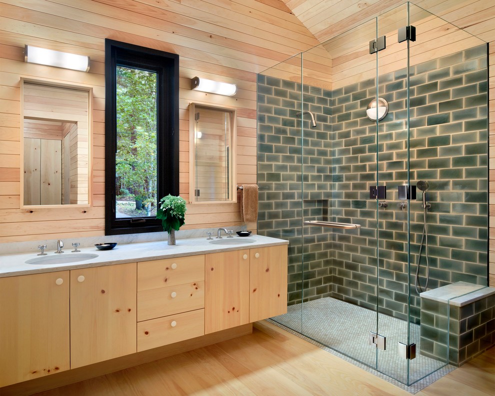 Arts and crafts bathroom in San Francisco with flat-panel cabinets, light wood cabinets, a corner shower, green tile, subway tile, light hardwood floors, an undermount sink and a hinged shower door.