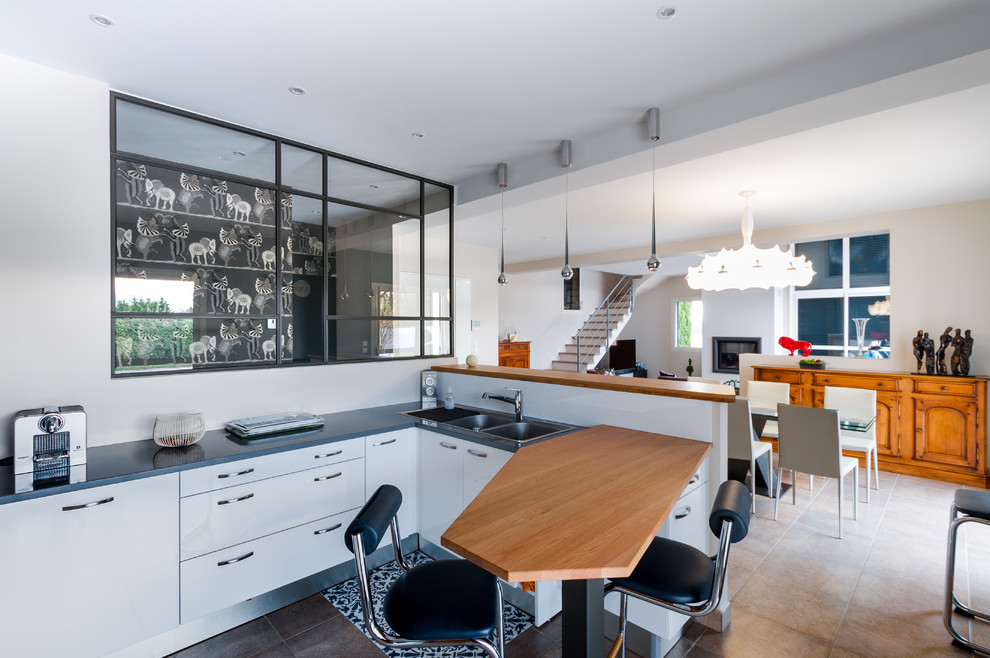 Design ideas for a mid-sized contemporary u-shaped eat-in kitchen in Lyon with white cabinets, wood benchtops, stainless steel appliances, ceramic floors, a peninsula and beige floor.