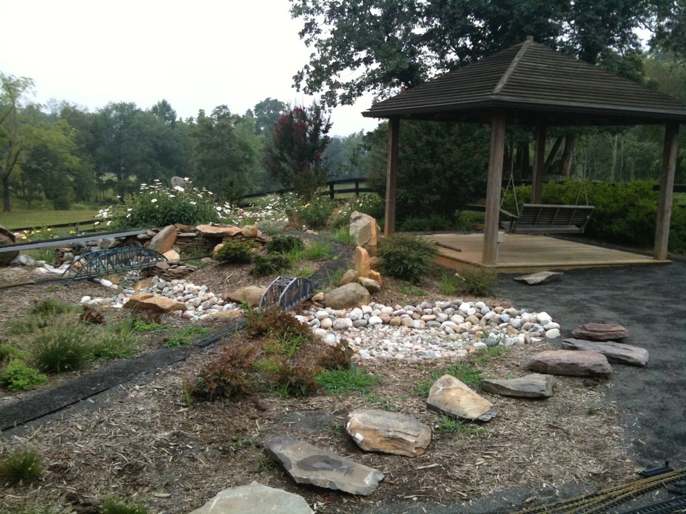 Design ideas for a large rustic partial sun backyard stone formal garden for summer.