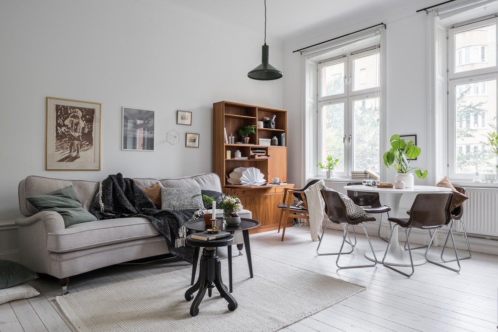 Mid-sized scandinavian formal open concept living room in Stockholm with white walls, painted wood floors and no tv.