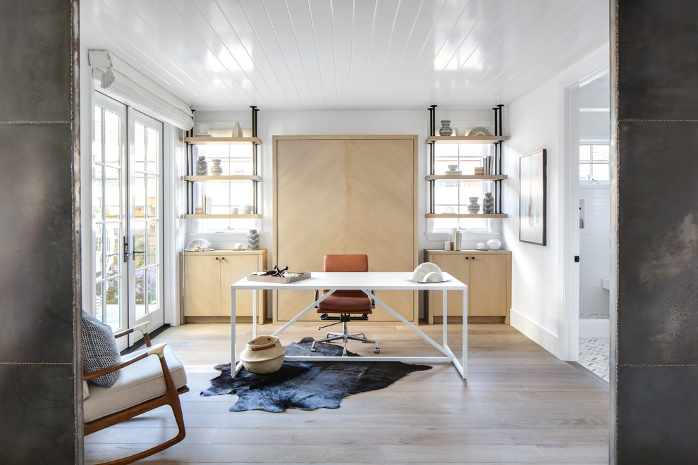 Inspiration for a beach style study room in Orange County with white walls, medium hardwood floors, a freestanding desk and brown floor.