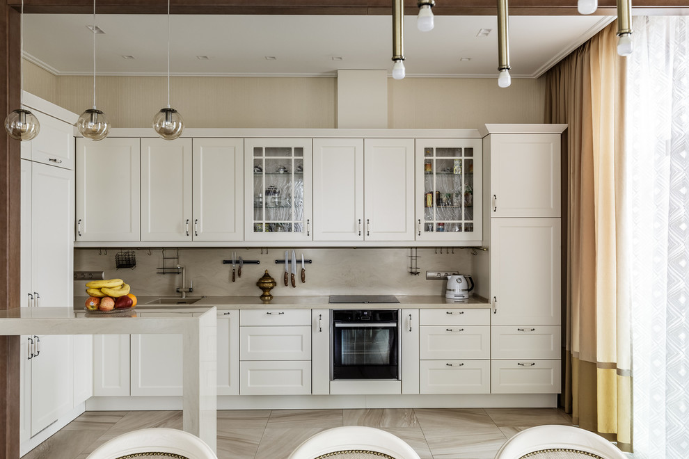 Photo of a transitional l-shaped open plan kitchen in Moscow with white cabinets, beige splashback, a peninsula, beige floor, beige benchtop, an undermount sink, recessed-panel cabinets and black appliances.