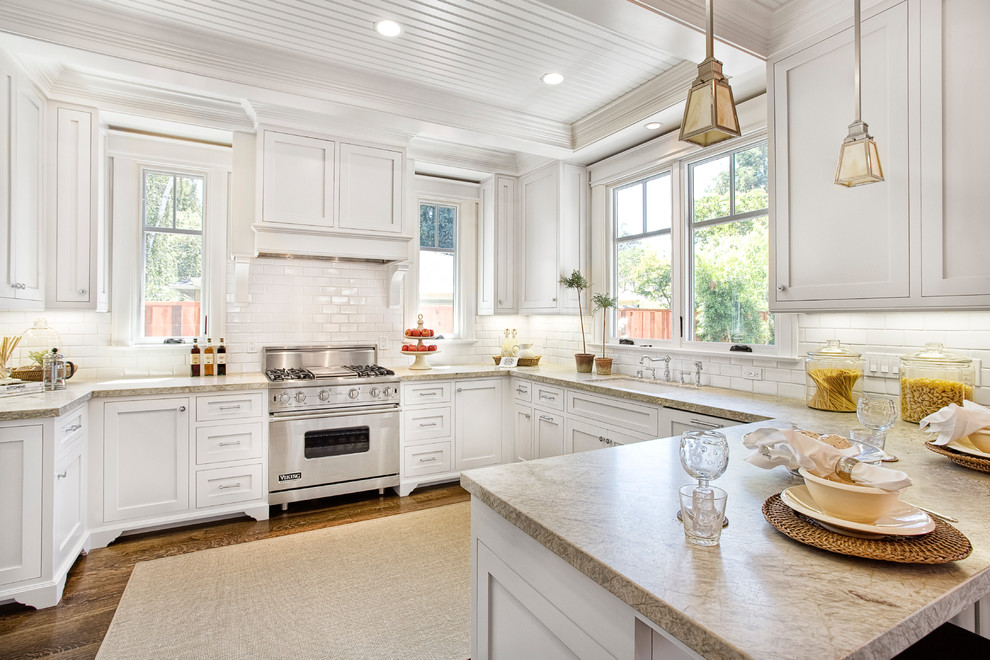 Photo of a traditional u-shaped kitchen in San Francisco with an undermount sink, shaker cabinets, white cabinets, white splashback, subway tile splashback and stainless steel appliances.
