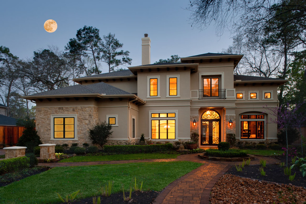 Large mediterranean two-storey stucco beige house exterior in Houston with a hip roof and a shingle roof.