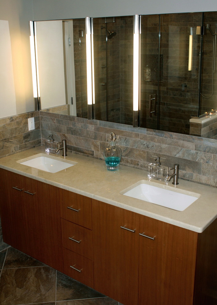 This is an example of a mid-sized asian master bathroom in New York with an undermount sink, flat-panel cabinets, medium wood cabinets, marble benchtops, an alcove tub, a double shower, a one-piece toilet, multi-coloured tile, porcelain tile, multi-coloured walls, porcelain floors, multi-coloured floor, a hinged shower door, beige benchtops, a shower seat, a double vanity, a freestanding vanity and vaulted.