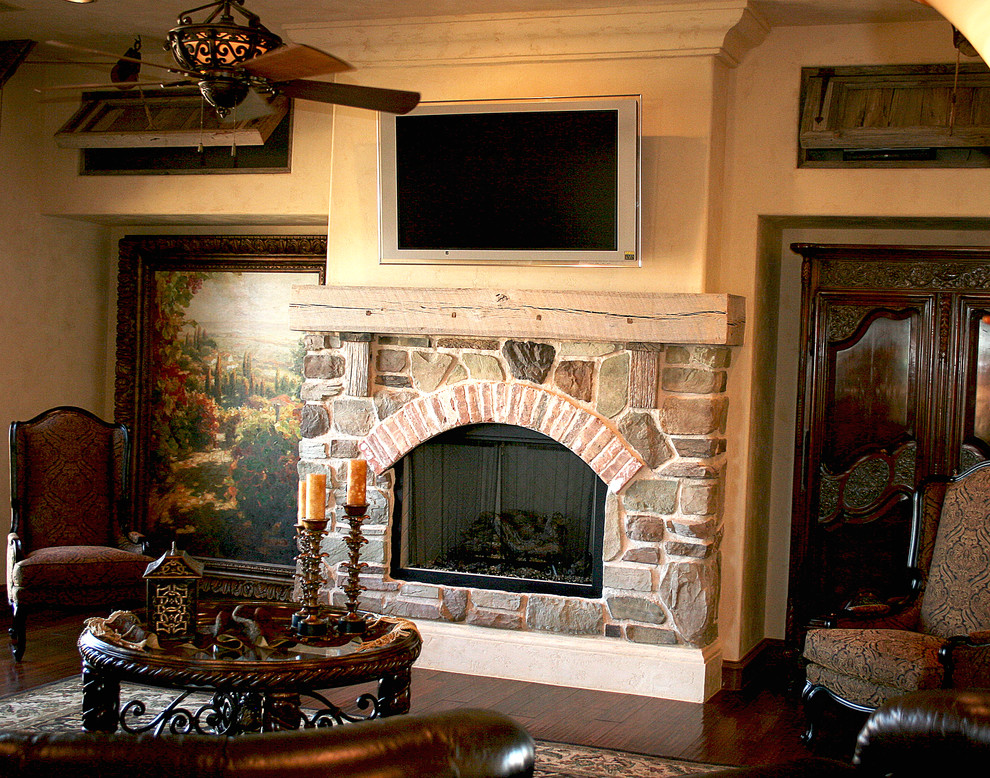 This is an example of a country family room in Austin with dark hardwood floors, a standard fireplace and a stone fireplace surround.