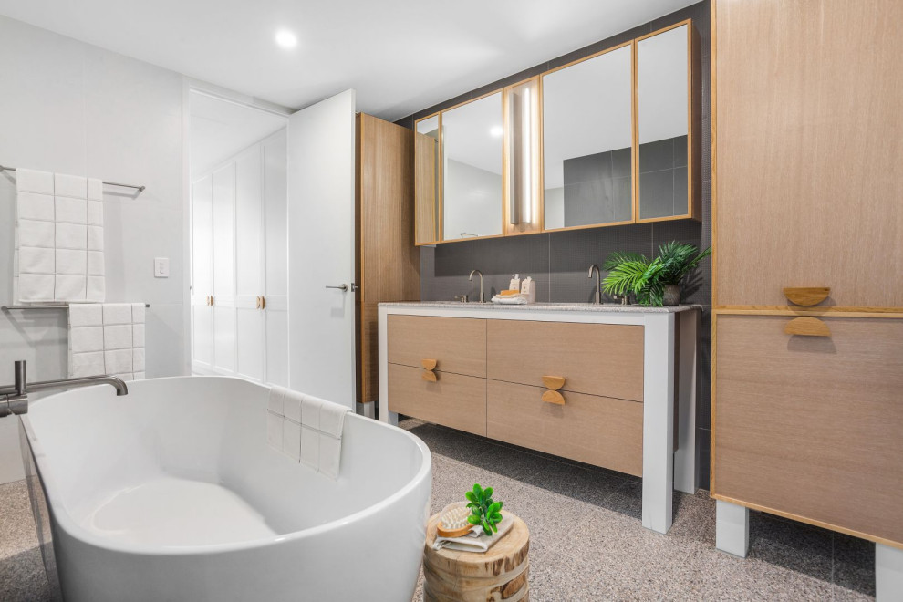 This is an example of a contemporary master bathroom in Central Coast with flat-panel cabinets, medium wood cabinets, a freestanding tub, gray tile, multi-coloured benchtops, a double vanity and a built-in vanity.