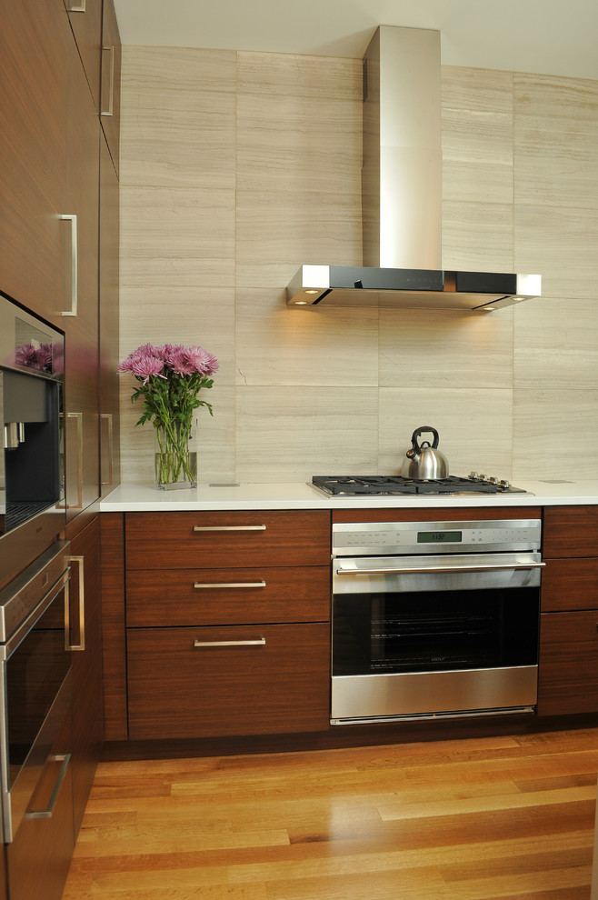 Photo of a mid-sized contemporary l-shaped open plan kitchen in Chicago with an integrated sink, flat-panel cabinets, dark wood cabinets, quartz benchtops, beige splashback, with island, light hardwood floors, stainless steel appliances and limestone splashback.
