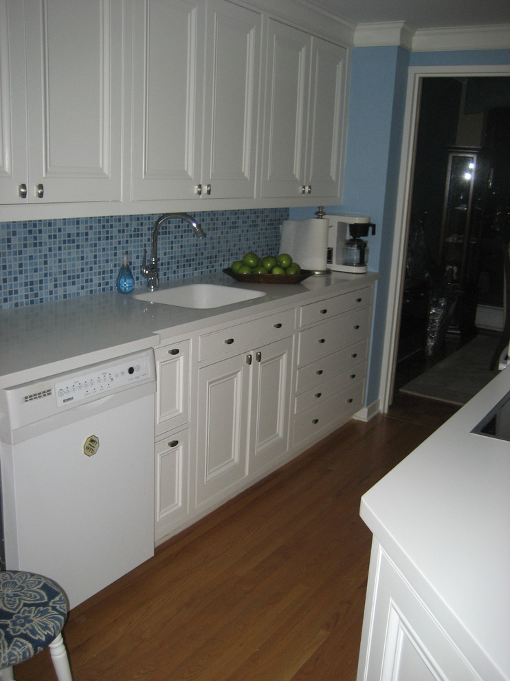 Inspiration for a small transitional galley separate kitchen in Ottawa with an integrated sink, recessed-panel cabinets, white cabinets, solid surface benchtops, blue splashback, mosaic tile splashback, white appliances, medium hardwood floors and a peninsula.