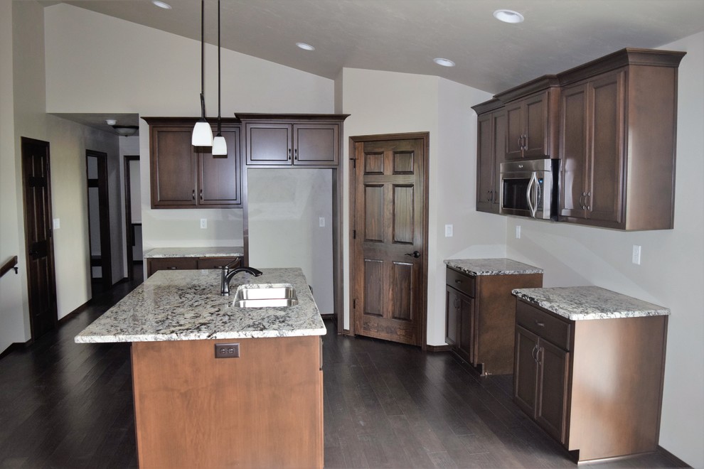 Example of a mountain style kitchen design with white cabinets, stainless steel appliances and an island