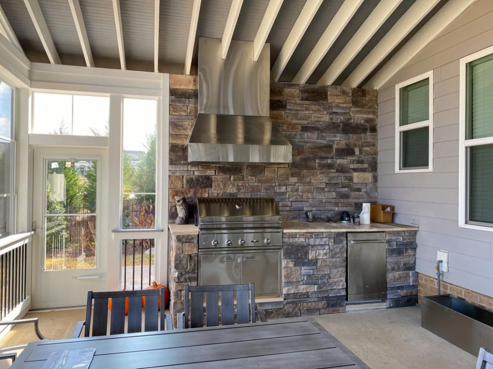 Cette image montre un grand porche d'entrée de maison arrière rustique avec une cuisine d'été, une extension de toiture et un garde-corps en matériaux mixtes.