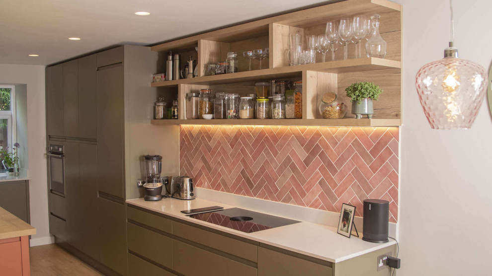This is an example of a mid-sized contemporary l-shaped eat-in kitchen in Sussex with flat-panel cabinets, light wood cabinets, quartzite benchtops, pink splashback, terra-cotta splashback, with island and white benchtop.