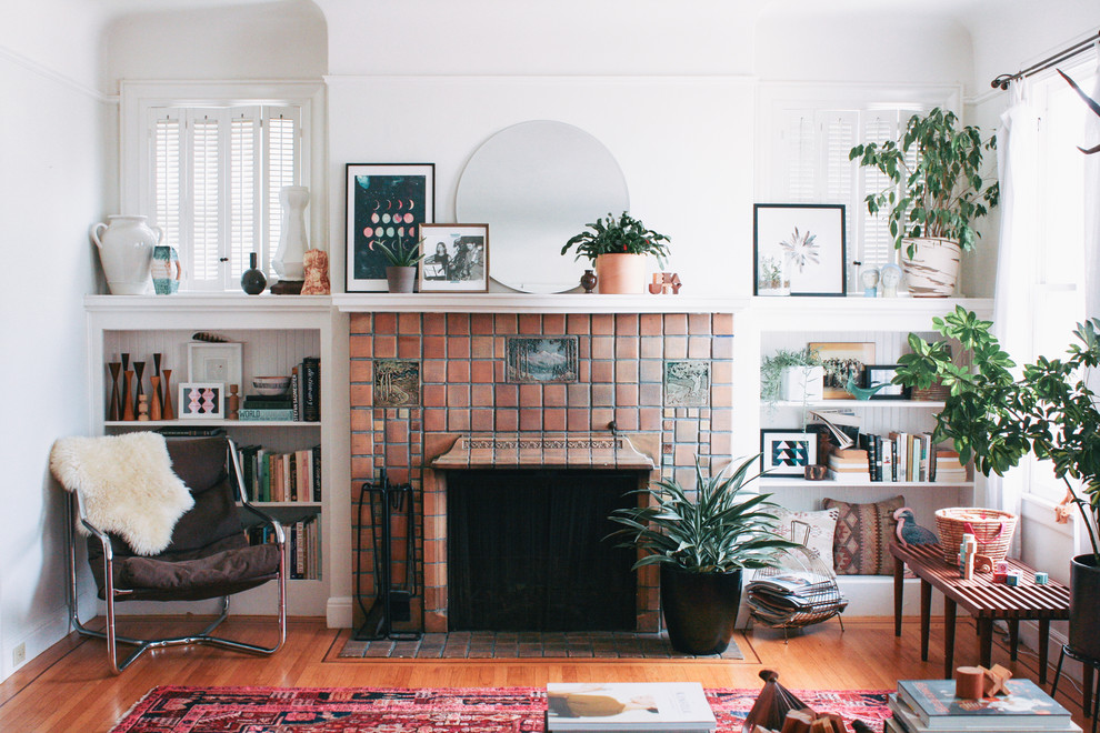 Inspiration for a small eclectic living room in San Francisco with a standard fireplace, a tile fireplace surround, white walls, medium hardwood floors and no tv.
