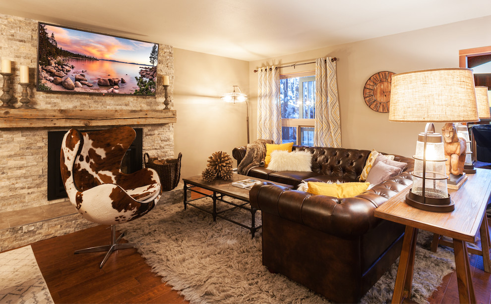 Inspiration for a country open concept living room in Other with brown walls, medium hardwood floors, a standard fireplace, a stone fireplace surround and a wall-mounted tv.