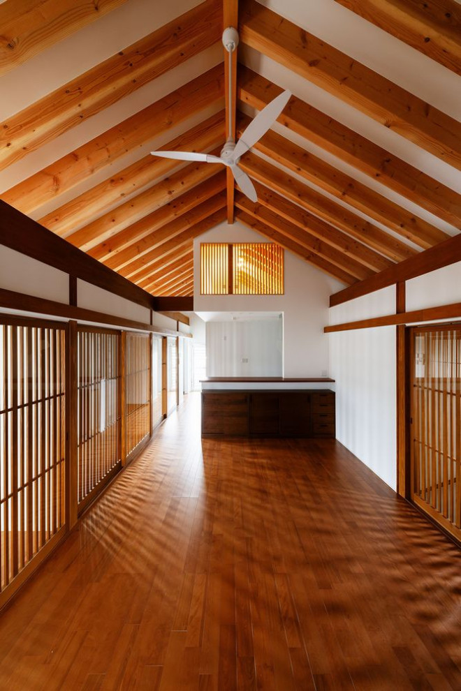 Photo of a large traditional open concept living room in Osaka with white walls, plywood floors, a freestanding tv and brown floor.